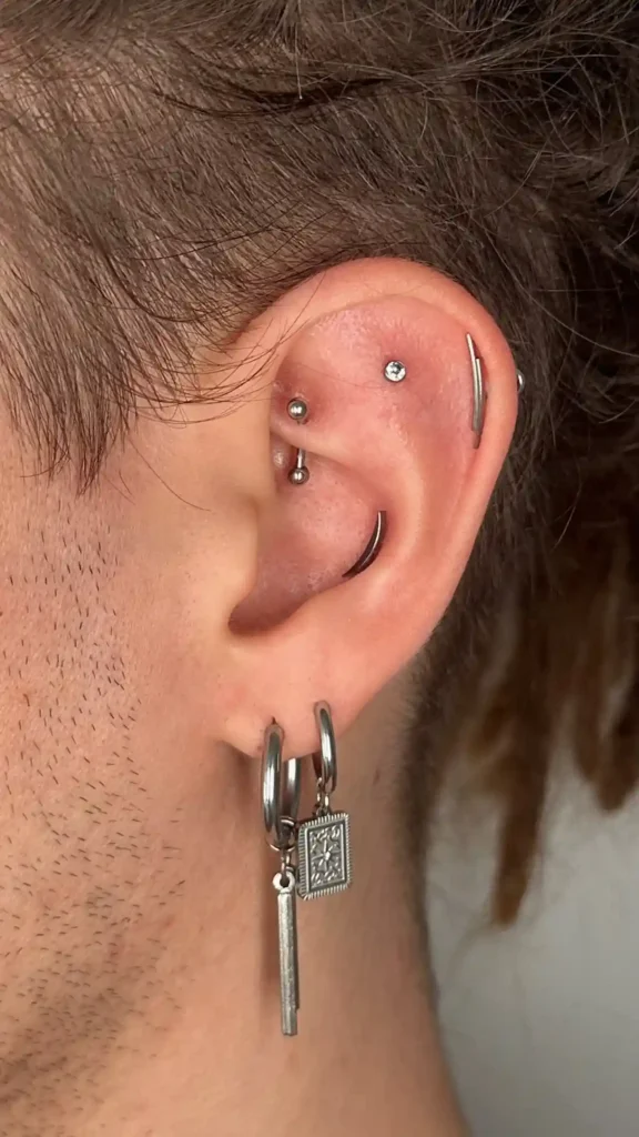 Oreja con piercings en el hélix y colgantes en el lóbulo
