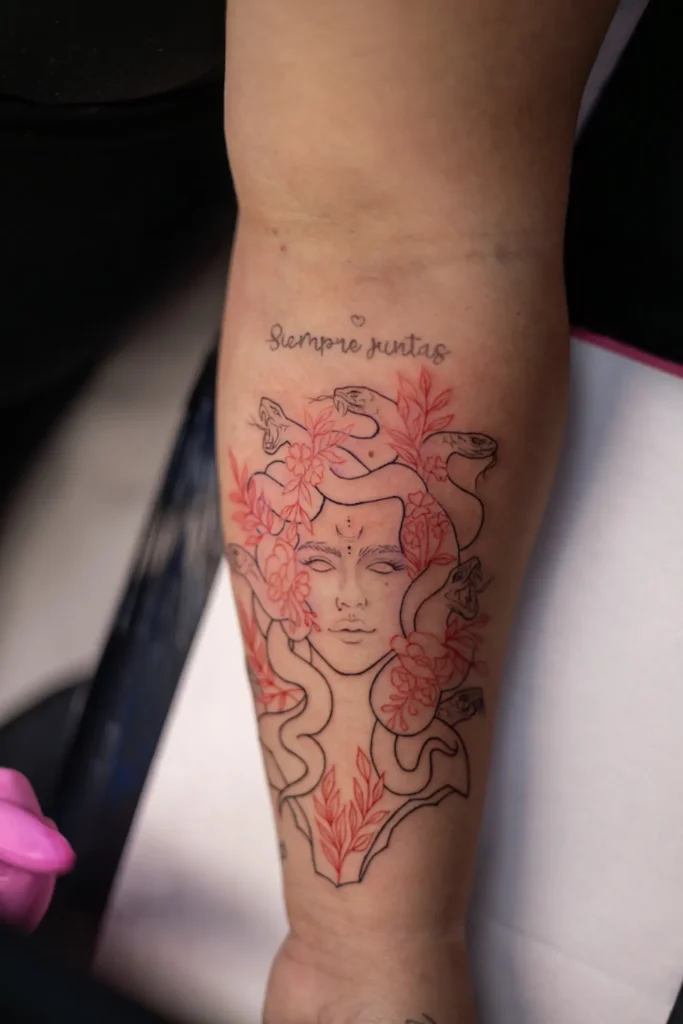 Medusa en fine line y tinta roja en el brazo