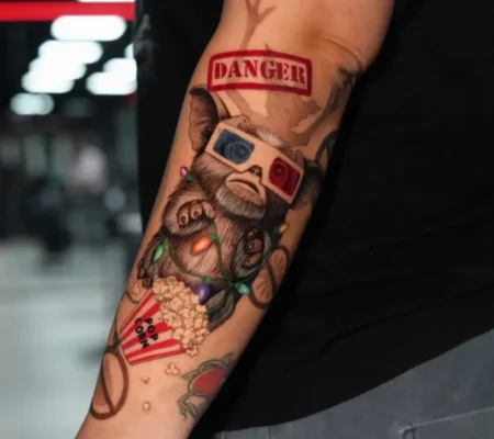 Tatuaje a color de mono con gafas 3D · Samantha Mono con gafas 3D, palomitas y cartel de Danger a color en el antebrazo