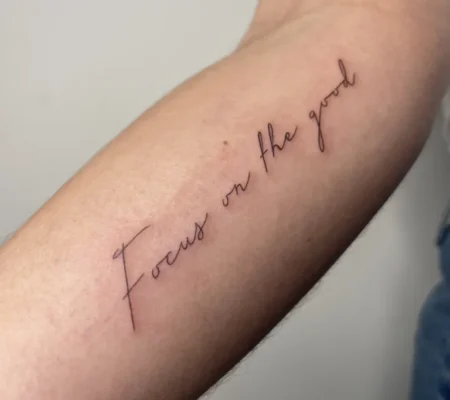 Tatuaje fine line con la frase Focus on the goal · Isabella Lettering en fine line con la frase Focus on the goal en el antebrazo