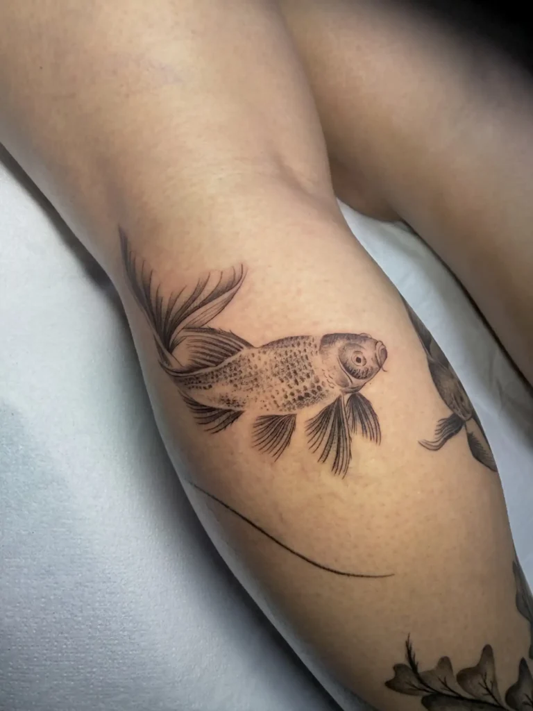 Pez betta con flores en fine line en el brazo